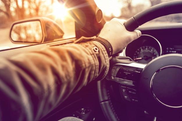 a_man_in_a_long_sleeved_jacket_with_his_left_hand_on_the_steering_wheel